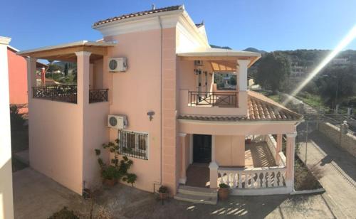 a small pink house with a balcony and a balcony at Anna Apartments in Acharavi