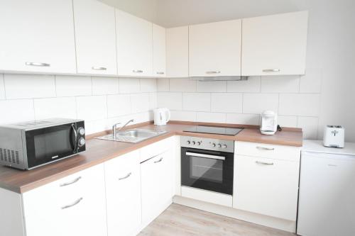 ペーネミュンデにあるSunny Apartment IIの白いキッチン(シンク、電子レンジ付)
