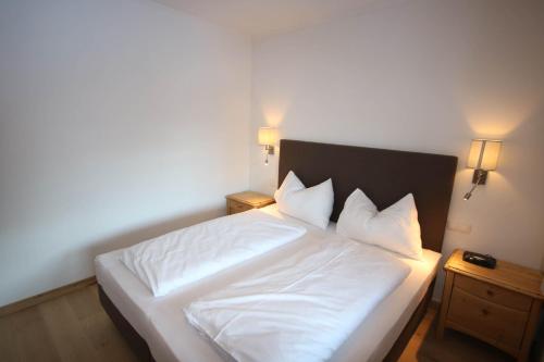 a bedroom with a white bed with two night stands at Appartementhaus Brunnenhof in Wagrain
