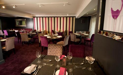 a restaurant with tables and chairs with wine glasses at Wharton Park Golf & Country Club in Bewdley