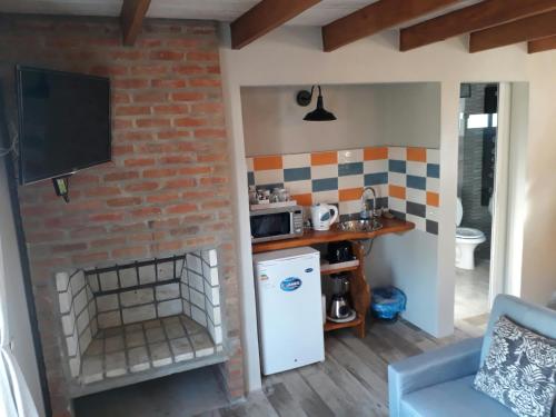 a kitchen with a brick wall and a white refrigerator at Il Tano Suites in Punta Del Diablo
