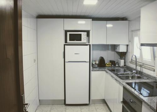 uma cozinha branca com um frigorífico e um micro-ondas em Huga Home em Lamego