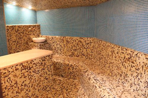 バンスコにあるElegant Lux Hotelのタイル張りのバスルーム(バスタブ、シンク付)