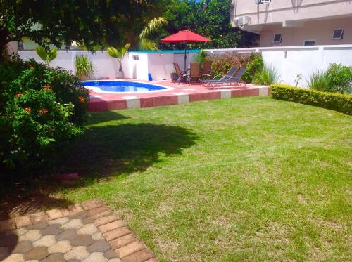 a backyard with a swimming pool and a lawn at Cardamon Villa is a 2 bedroom with 1 bathroom and seperate toilet detached house with AC and swimming pool , 5 minutes walk from Flic en Flac public beach in Flic-en-Flac