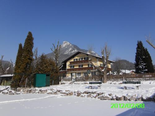a house in the snow with benches in front of it at Pension Salzburger Hof in Fuschl am See