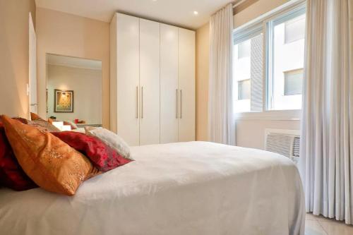um quarto com uma cama branca e uma janela em HomeStay 3 - Avenida Carlos Gomes em Porto Alegre