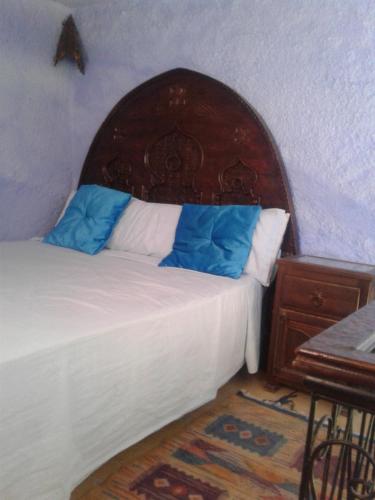 a bedroom with a bed with a wooden headboard at Dar Lbakal in Chefchaouene
