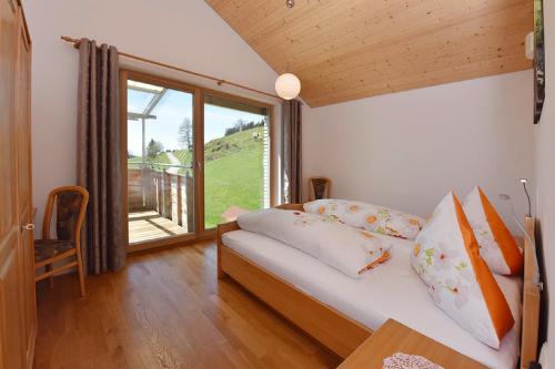 a bedroom with a bed and a large window at Ferienhof Feurle in Sulzberg