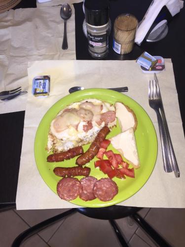 a green plate of food with sausage and eggs at Pensiunea Zbor in Cluj-Napoca