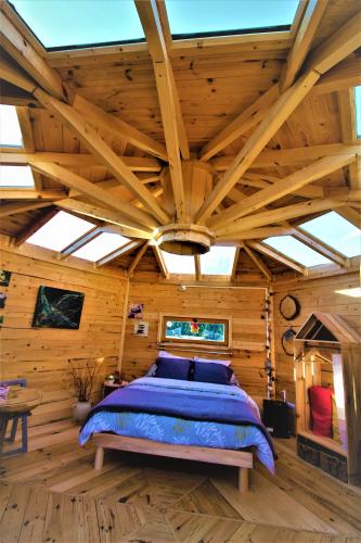 une chambre avec un grand lit dans une pièce en bois dans l'établissement Eco Yourte, à Sembadel