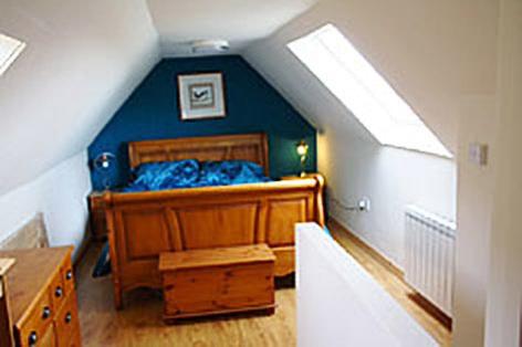 een slaapkamer met een bed met blauwe lakens op een zolder bij Sealoch Cottage in Breasclete