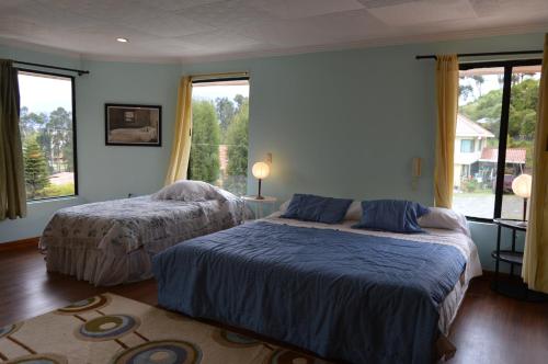 a bedroom with two beds and two windows at NUESTRA CASA - OUR HOME Cuenca by A2CC in Ricaurte