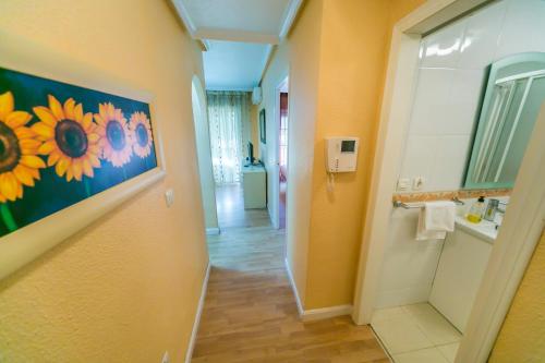 a bathroom with a painting of flowers on the wall at Homely Apartments Calle Apolo in Torrevieja