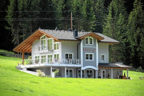 a large house on a hill in a field at Ferienwohnung Höllrigl in Sankt Leonhard im Pitztal