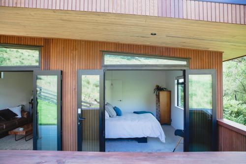 een slaapkamer in een huis met glazen schuifdeuren bij Amongst The Nikau in Waihi Beach