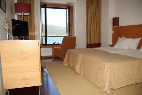 a hotel room with a bed and a window at Douro Hotel Porto Antigo in Cinfães