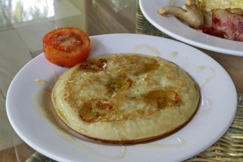 a plate of food with a pancake and a tomato at Mutiara Bali in Candidasa
