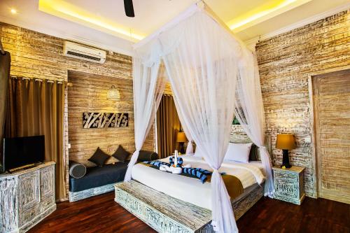 a bedroom with a canopy bed and a tv at The Palm Grove Villas - CHSE Certified in Nusa Lembongan