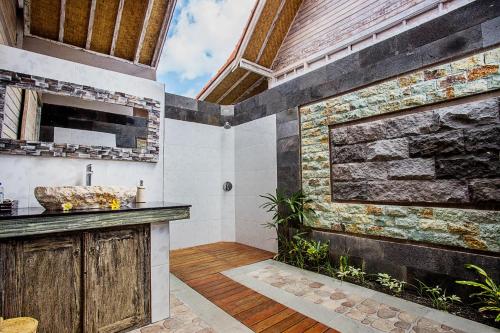 a bathroom with a sink and a stone wall at The Palm Grove Villas in Nusa Lembongan