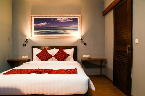 um quarto com uma grande cama branca com almofadas vermelhas em Wae Molas Hotel em Labuan Bajo