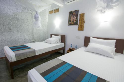 two beds in a room with white walls at Udawatta Kele (UK) Forest Lodge in Kandy