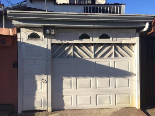 a white garage door with a roof at Guesthouse Casa Lapa in Alajuela City