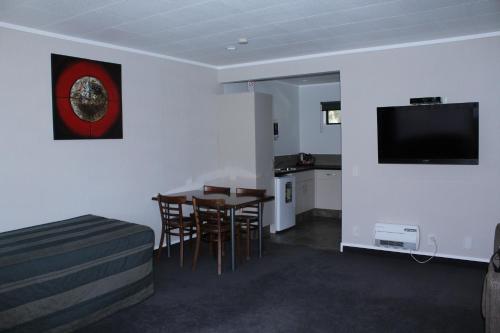 a living room with a table and a tv on the wall at Rose City Motel in Palmerston North