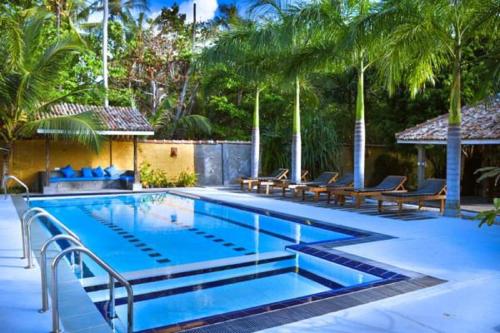 ヒッカドゥワにあるHotel Vibrationのベンチとヤシの木があるスイミングプール