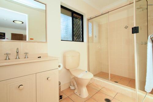 a bathroom with a toilet and a glass shower at Rockhampton Palms Motor Inn in Rockhampton