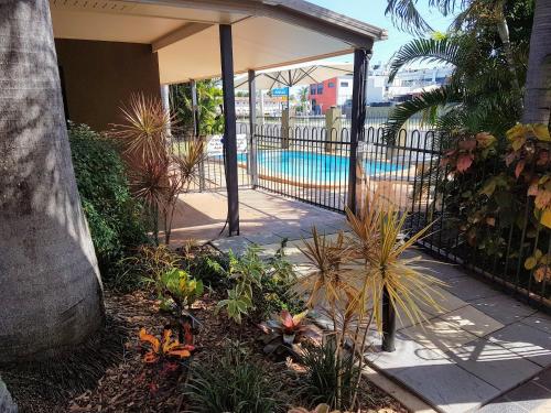 a garden with a fence and a swimming pool at Rockhampton Palms Motor Inn in Rockhampton
