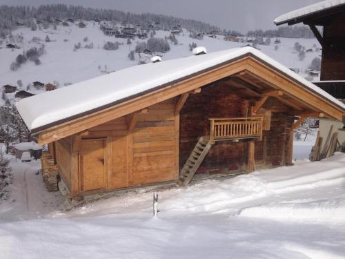 a log cabin with a snow covered roof at La Ferme des Georgières "Séjour en tout compris" in Notre-Dame-de-Bellecombe