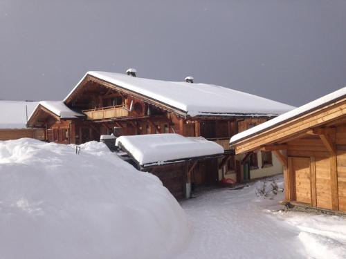 a house covered in snow with a pile of snow at La Ferme des Georgières "Séjour en tout compris" in Notre-Dame-de-Bellecombe