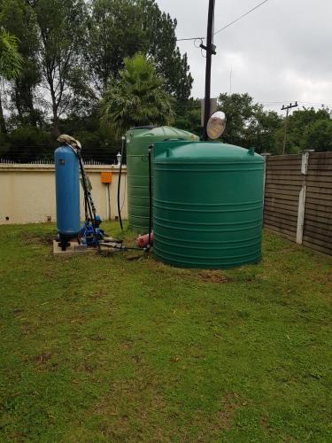 two water tanks sitting on the grass in a yard at 12 On Vaal Drive Guesthouse in Vanderbijlpark