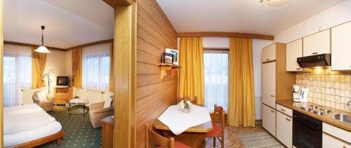 a hotel room with a kitchen and a living room at Haus Sonnleit in Kössen