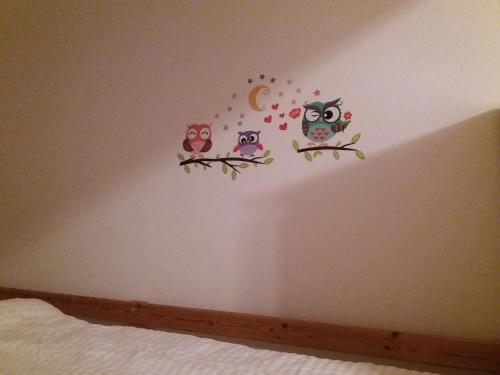 four owls on branches on a bedroom wall at Gästehaus Auszeit in Unterlamm