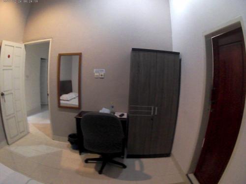 a room with a desk and a chair and a mirror at Wisma Maharani in Wanci