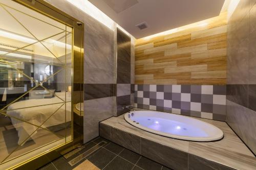 a bathroom with a tub and a glass shower at Soho Motel in Taoyuan