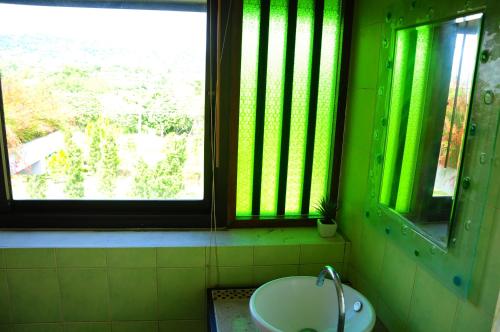 a green bathroom with a sink and two windows at Phumimalee Nature View Resort in Nakhon Ratchasima