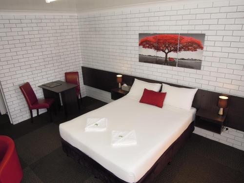 1 dormitorio con 1 cama con un árbol rojo en la pared en Jackaroo Apartments, en Moree