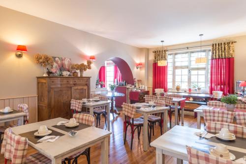 a restaurant with tables and chairs and red curtains at Villa Bon Repos in Argelès-Gazost