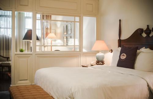 a bedroom with a large white bed and a window at Hotel Majapahit Surabaya MGallery in Surabaya
