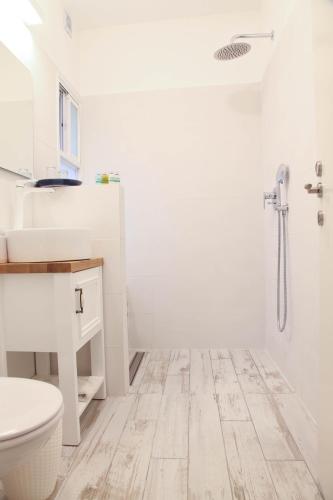 a white bathroom with a toilet and a shower at Bar Bakfar in Sharona