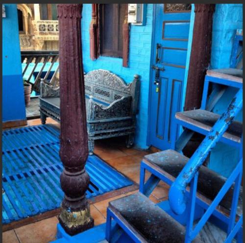 a blue house with a blue pole and a chair at The Blue House in Jodhpur