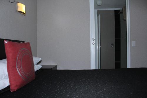 a bedroom with a bed with a red pillow on it at Rose City Motel in Palmerston North