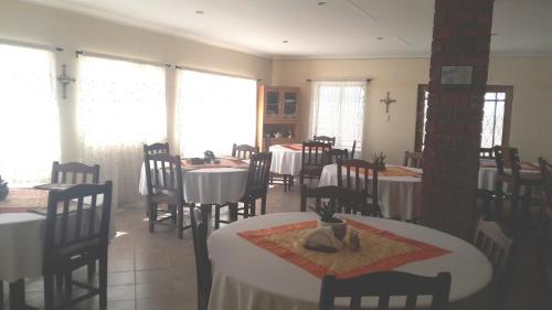 a dining room with tables and chairs and windows at Tismaree Guestfarm in Rietoog