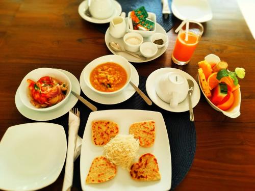 a table with plates of food and bowls of food at Unawatuna Nor Lanka Hotel in Unawatuna