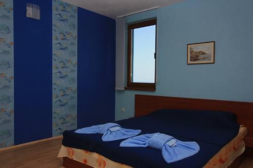 um quarto com uma cama com paredes azuis e uma janela em Complex Koral em Sinemorets