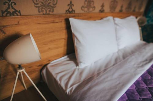 a bed with a white pillow and a lamp at Hotel Korzo in Bitola