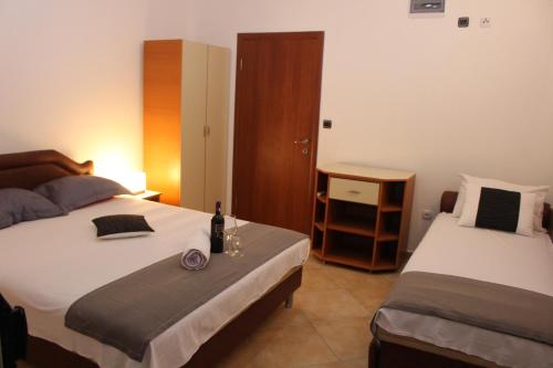 1 dormitorio con 2 camas y 1 botella de vino en Apartments Perezaj II, en Ulcinj