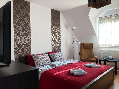 a bedroom with a red bed and a television at Domek Sewerynowka in Szczawnica